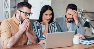 3 shocked people looking at laptop