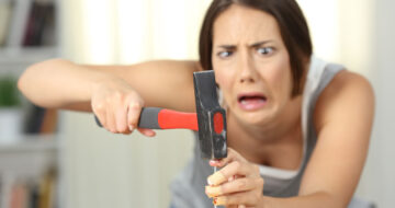 Woman hitting finger with hammer